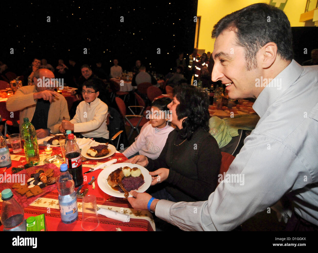 Vorstandsvorsitzender der Green Party Cem Oezdemir (R) dient Gänsebraten auf das traditionelle Weihnachtsessen für Obdachlose im Hotel Estrel in Berlin-Neukölln, Deutschland, 19. Dezember 2012. Das Weihnachtsessen wurde von Frank Zander, gemeinnütziger Verein Diakonisches Werk und Hotel Estrel seit 18 Jahren organisiert. Foto: BRITTA PEDERSEN Stockfoto