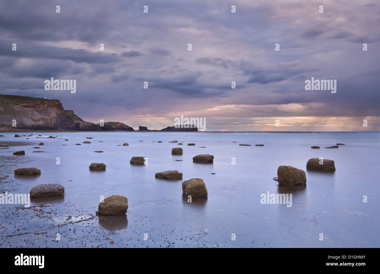 Riesige Felsbrocken bei Ebbe in gegen Bucht mit regnerisch Wetter über gegen Nab, North Yorkshire, Yorkshire, England Stockfoto