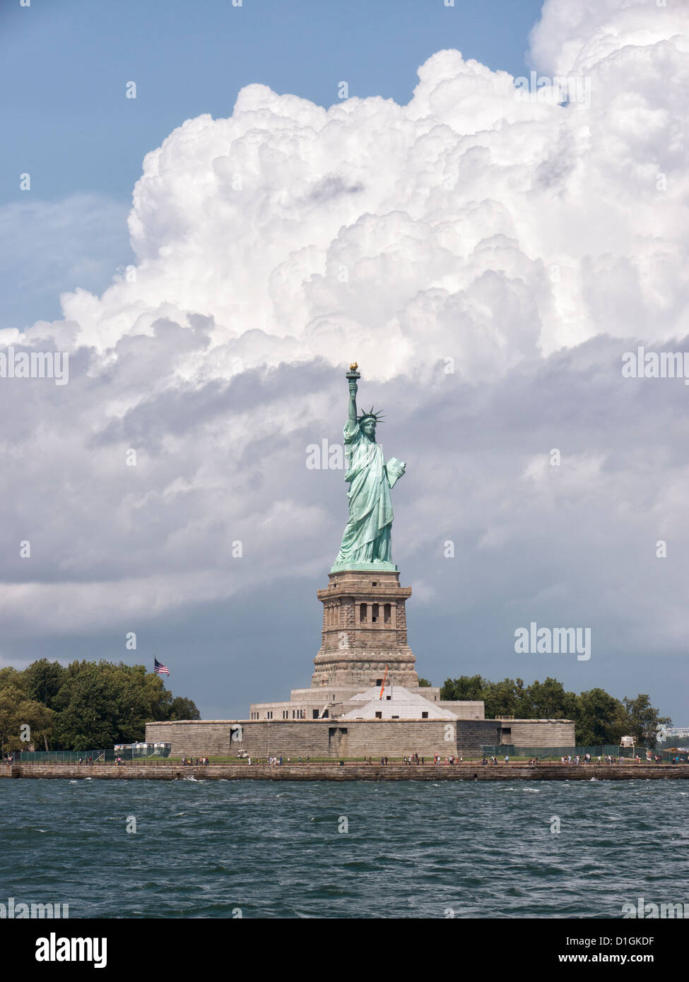 Die Welt berühmte Freiheitsstatue auf LIberty Island im New Yorker Hafen mit einem beeindruckenden Build Wolke hinter. Stockfoto