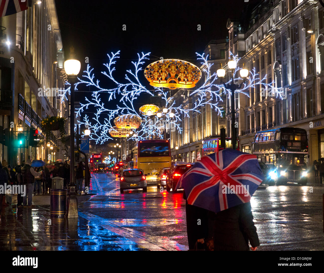 Weihnachts-Einkäufer, Verkehrs- und Union Jack flag Regenschirm in einem Regen fegte die Regent Street mit Weihnachtsbeleuchtung hinter London UK Stockfoto