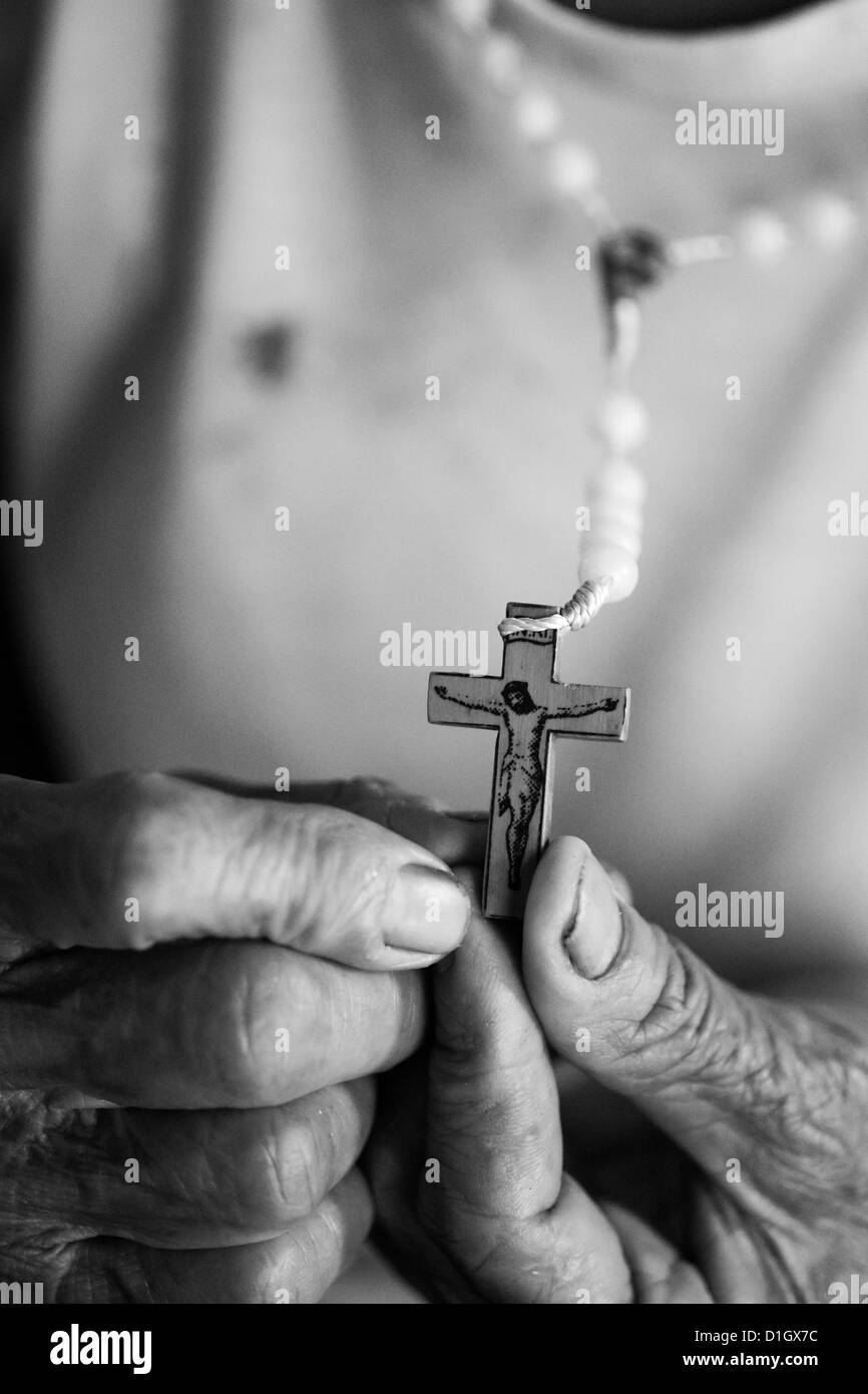 Schwarz weißes Bild eines Kruzifixes in eine ältere Womans Hand gehalten Stockfoto