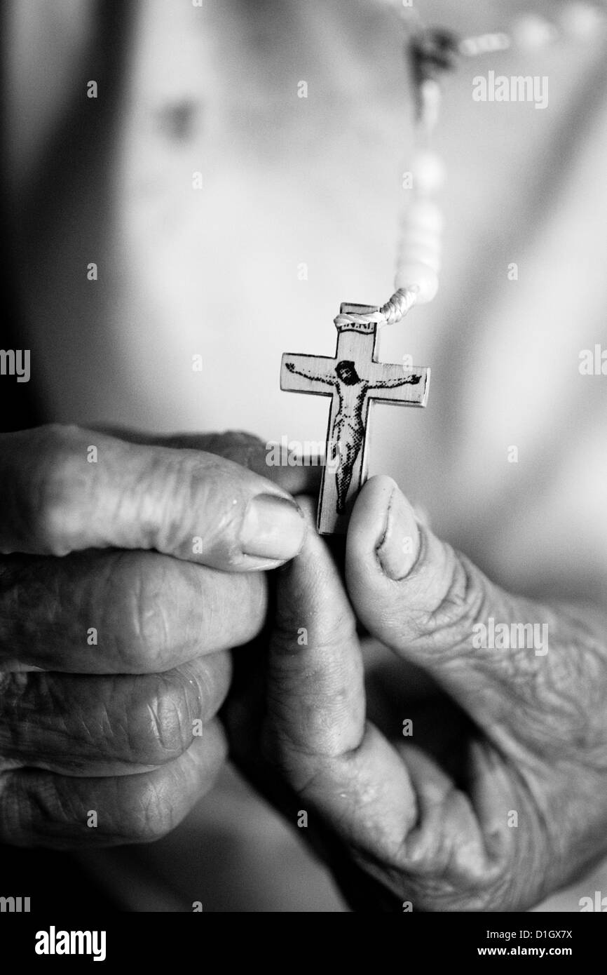 Schwarz weißes Bild eines Kruzifixes in eine ältere Womans Hand gehalten Stockfoto