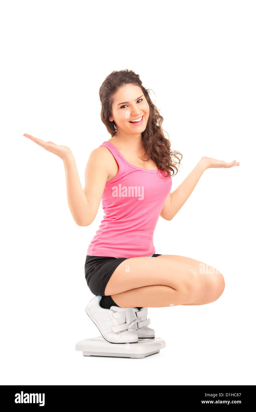 Eine glückliche Frau auf ein Gewicht Waage gestikulieren mit den Händen auf weißen Hintergrund isoliert Stockfoto