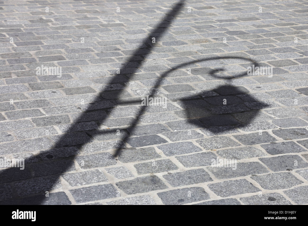 Schatten einer Straßenlaterne auf dem Bürgersteig Stockfoto