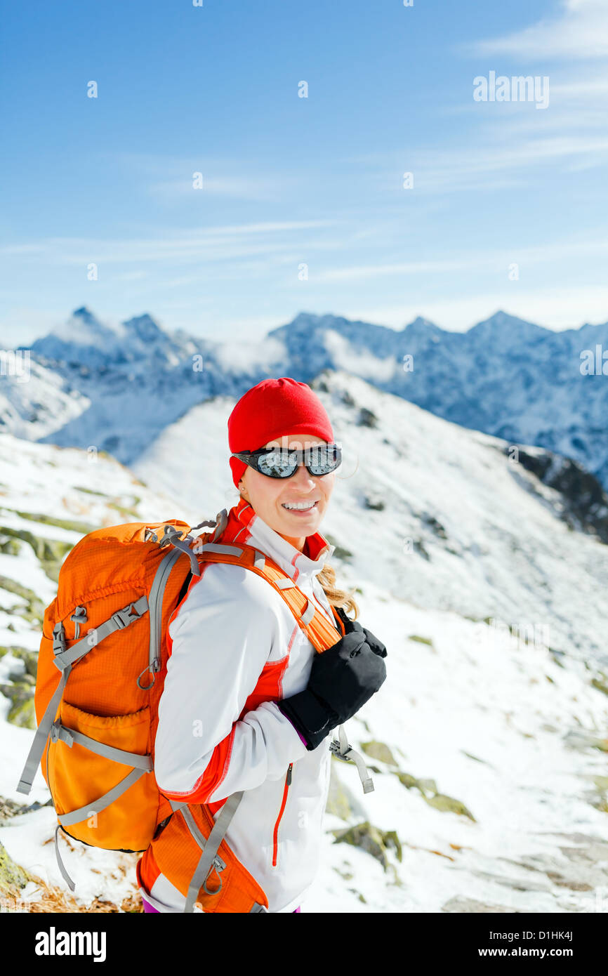Junge Frau im Winterberge Wandern lächelnd zu Kamera Stockfoto