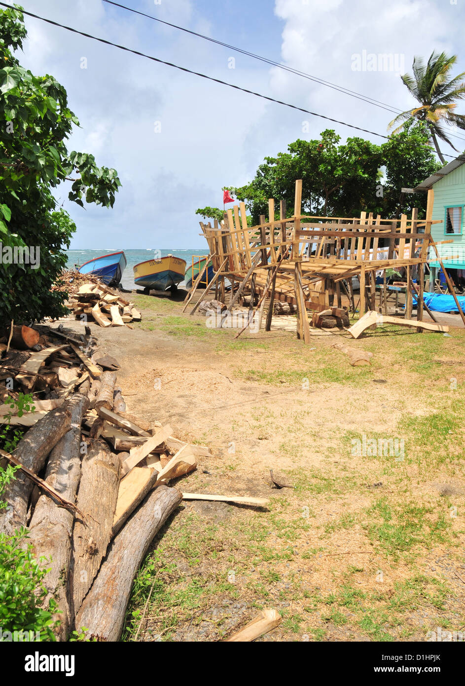 Blauer Himmel weiße Wolken anzeigen grünen Strand oben clearing-Haus mit Zeder Holz-Bootsbau, Grenville Bay, Grenada, West Indies Stockfoto