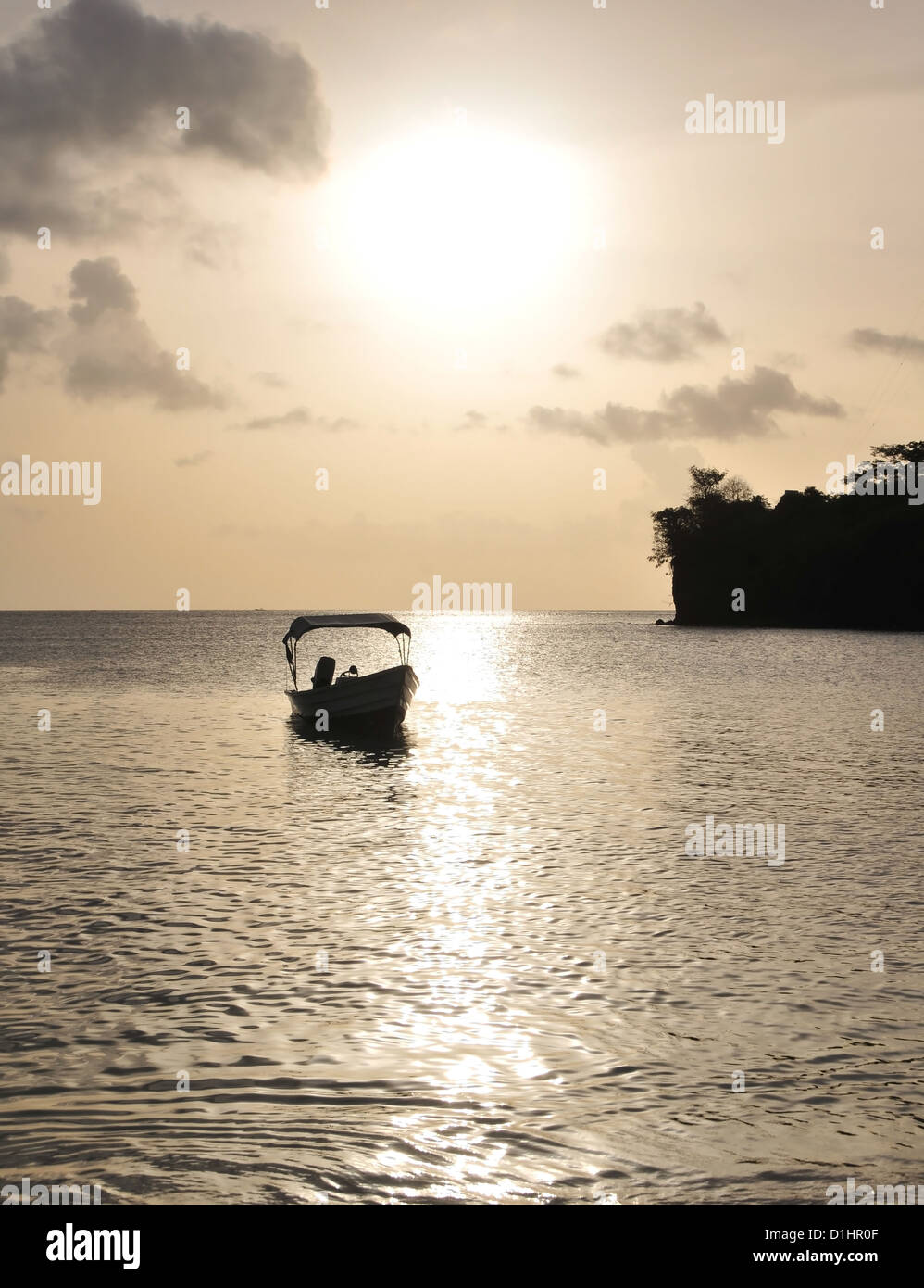 Kleines Boot verankert in einem silbernen Meer unter einer goldenen Himmel weiße Kugel untergehenden Sonne, Nordende Morne Rouge Strand, Grenada, West Indies Stockfoto
