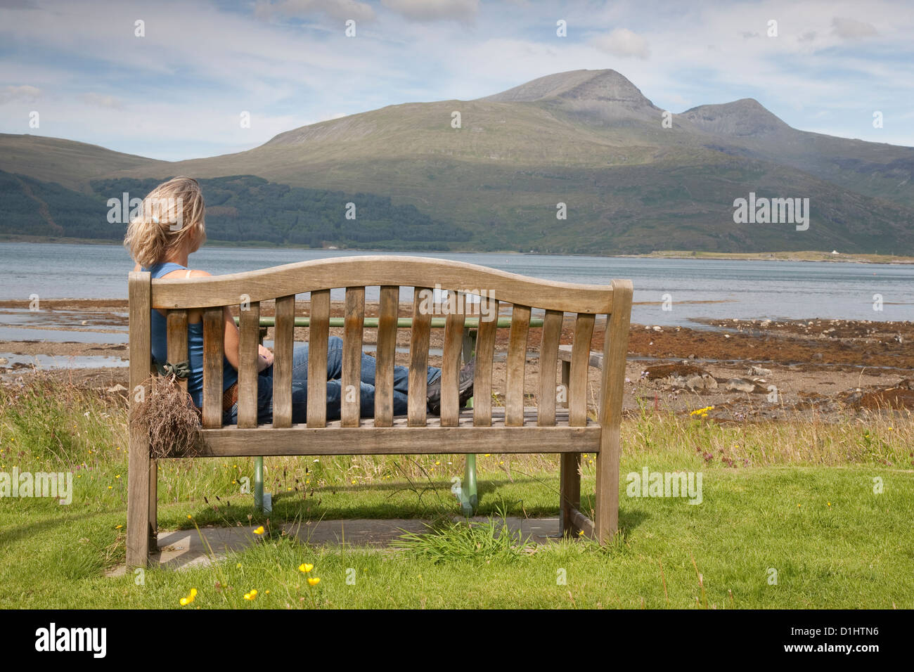 Junge Frau sitzt auf der Bank auf der Isle of Mull, Schottland Stockfoto