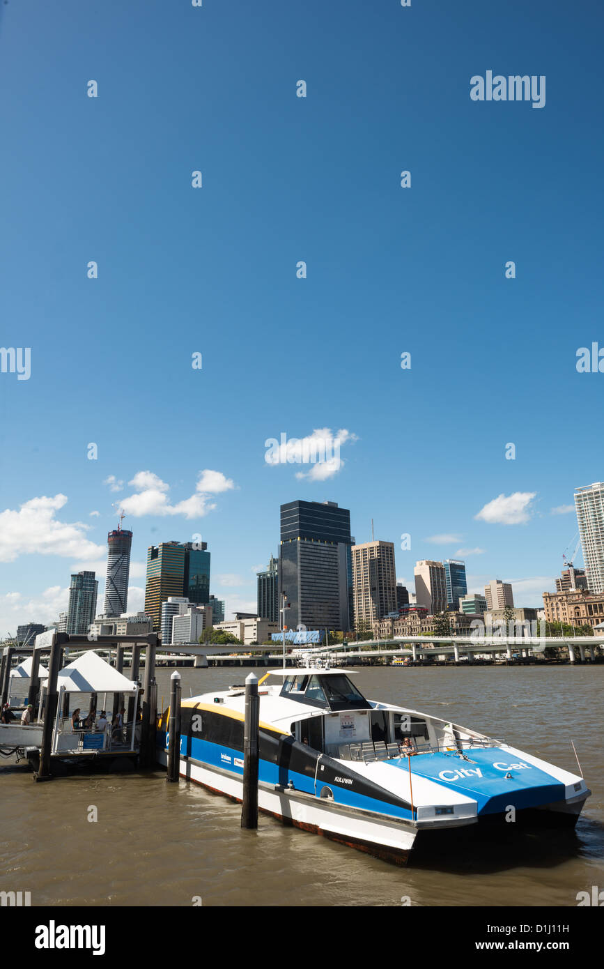 Eine Citycat Fähre hochgezogen, ein Fährhafen am Südufer, mit der Skyline von Brisbane im Hintergrund aus über den Brisbane River. Die CityCat bieten eine ÖPNV-Option für die Verwendung des Flusses, der windet sich durch das Zentrum der Stadt. Stockfoto