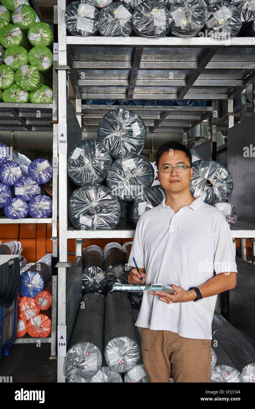 Ein Manager mit einem Klemmbrett steht neben einer Palette der Walze Stoff Stockfoto