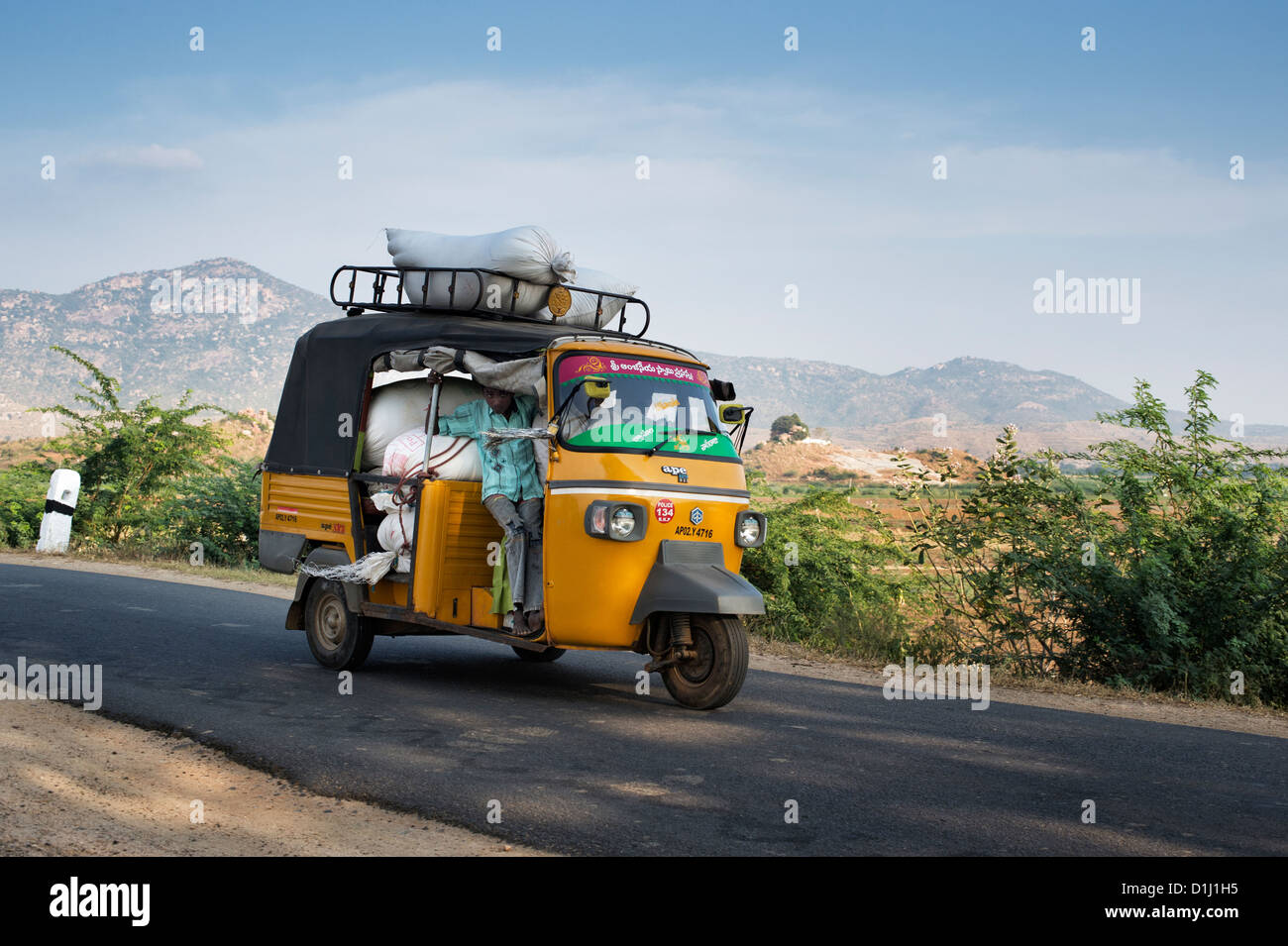 Indische Autorikscha überladen mit Säcken Reis auf einer Landstraße. Andhra Pradesh, Indien Stockfoto