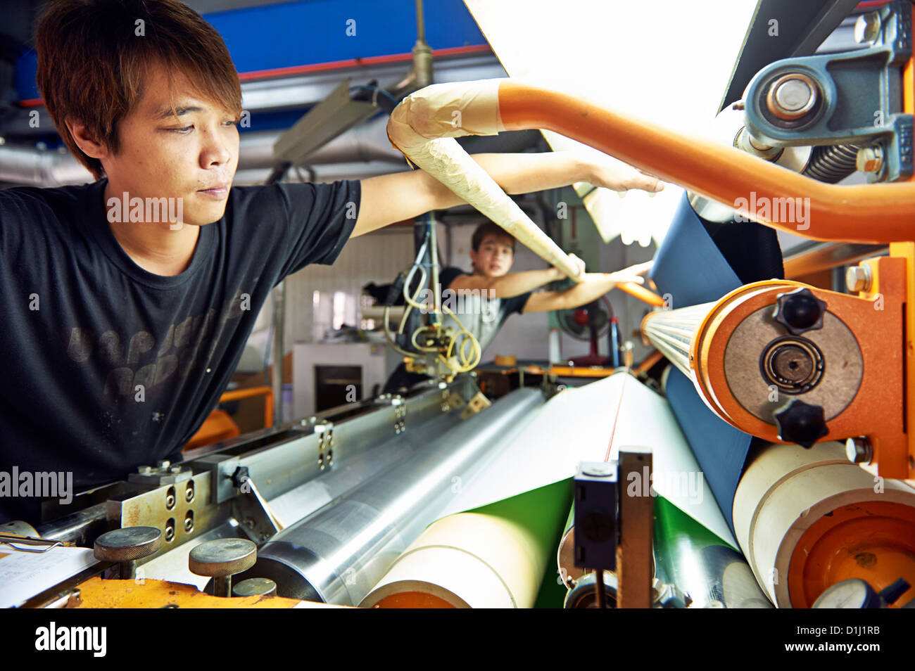 Ein Arbeiter inspiziert Stoff aus einer Walze Stockfoto