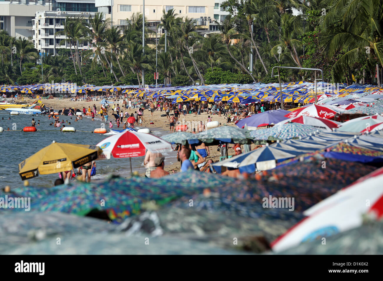 Strand-Szene mit Sonnenschirmen und Massen an der Strandpromenade von Pattaya, Thailand Stockfoto