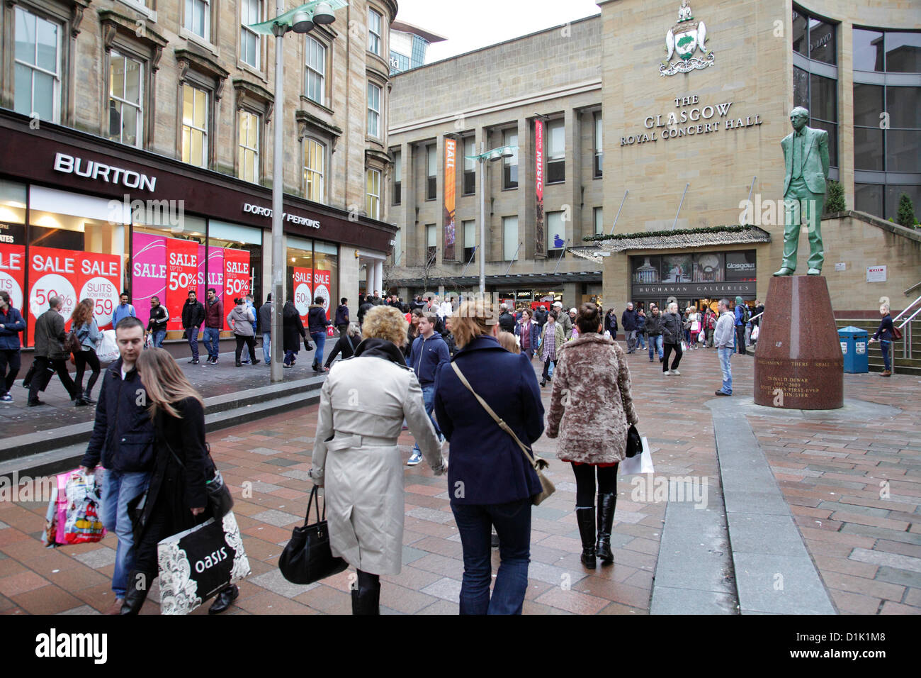 Buchanan Street, Glasgow, Schottland, Großbritannien, Mittwoch, 26th. Dezember 2012. Leute, die beim Verkauf am Boxing Day im Stadtzentrum neben dem Einkaufszentrum Buchanan Galleries einkaufen, mit der Statue des ehemaligen Ersten Ministers Donald Dewar, die im Stadtzentrum aufschaut Stockfoto