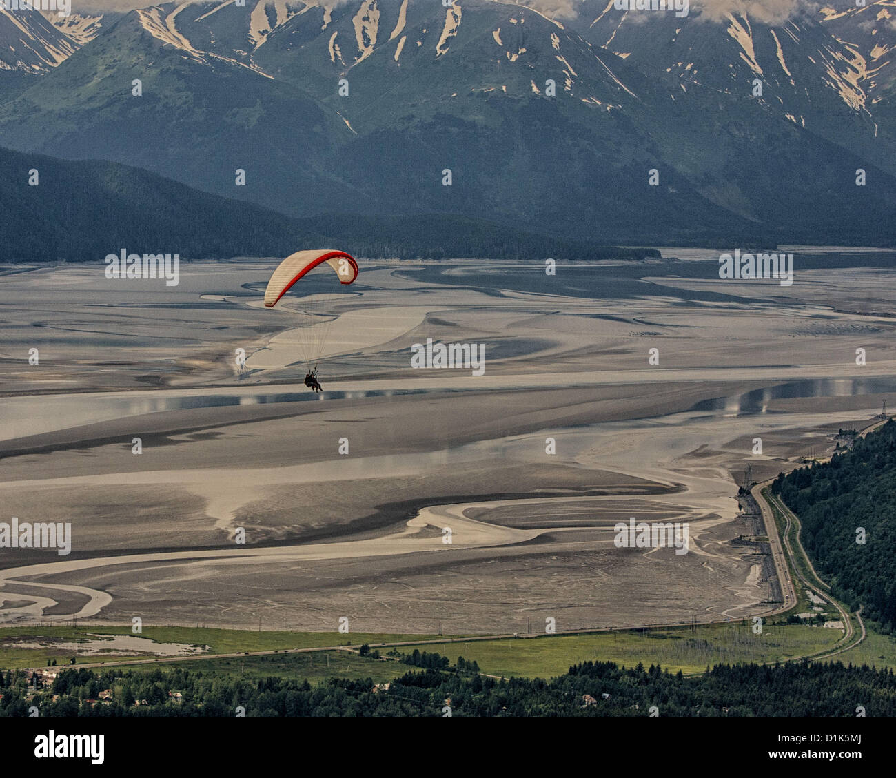 30. Juni 2012 - Girdwood, Alaska, USA - Gleitschirme in ein Tandem-Gurtzeug ausgesetzt unter einem wallenden Stoff Flügel erhalten eine atemberaubende Birdâ€™ s Auge Ansicht des imposanten schneebedeckten Kenai Gebirges, wie sie überfliegen Turnagain Arm [hier bei Ebbe] nach dem Start von Mt Alyeska.  Ein 50 mi [80 km] Fjord von Cook Inlet, bemerkenswerte Turnagain Arm gefüttert hat die größten Gezeiten-Zyklus-Schwankungen in den USA befindet sich in Girdwood, Alaska, 27 Meilen (44Â km) von Anchorage, Mt. Alyeska, der größten Skiberg im Zustand, ist ein Lieblings Startplatz für Gleitschirmflieger. (Kredit-Bild: © Arnold Drapkin/ZUMAPRESS Stockfoto