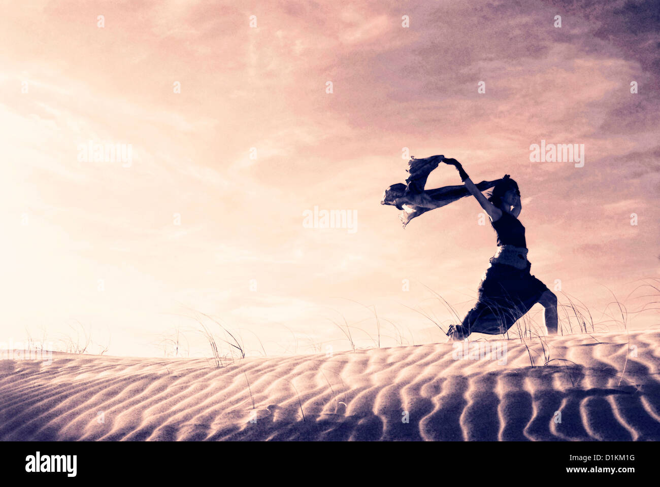Silhouette einer Frau mit einem wehenden Schal in den Dünen. Stockfoto