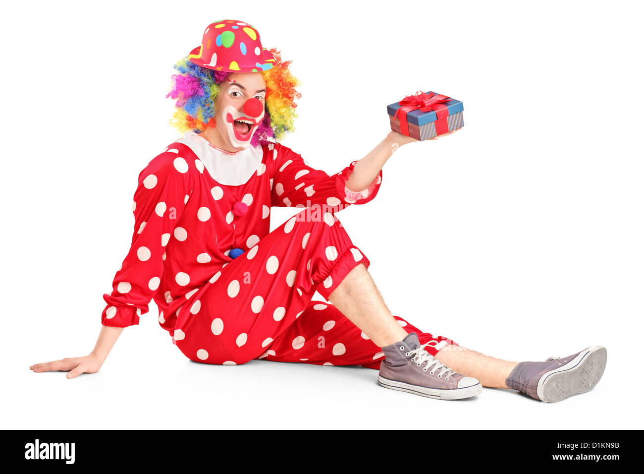 Ein Lächeln auf den Lippen Clown auf einer Etage hält ein Geschenk isoliert auf weißem Hintergrund Stockfoto