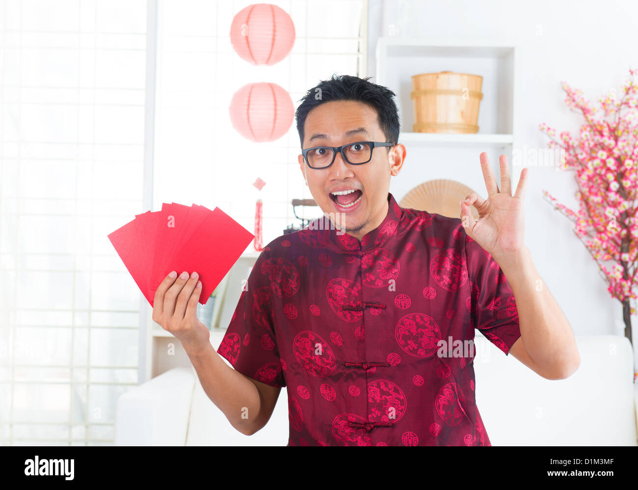 Okay Handzeichen südostasiatischen chinesischer Mann zeigt viele rote Pakete / Ang pow im Innenbereich Stockfoto