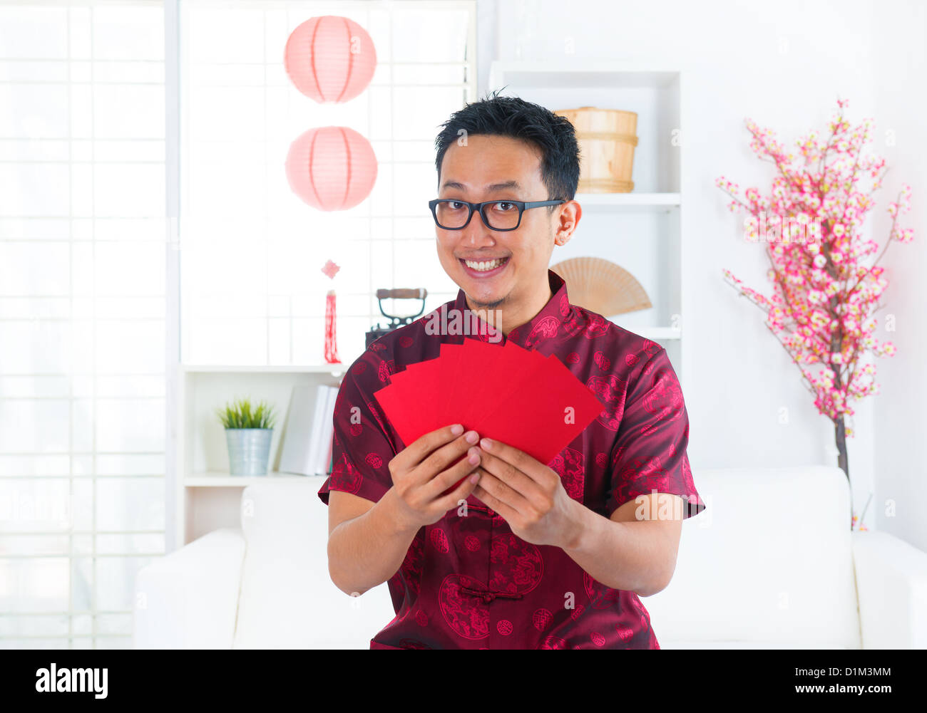 Südostasiatische chinesischer Mann zeigt viele rote Pakete / Ang pow im Innenbereich Stockfoto