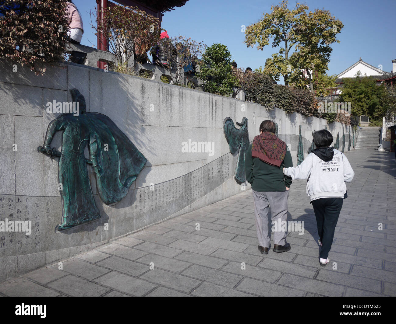 chinesisches Ehepaar zu Fuß passieren chinesischer Poesie Wand Stockfoto