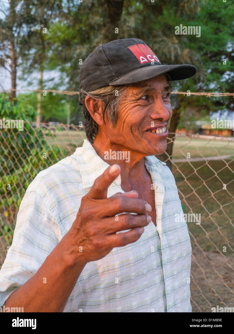 Ein paraguayischer Mann trägt eine schwarze Baseballkappe mit einem rot-weißen Logo drauf lächelt und Gesten in Filadelfia, Paraguay. Stockfoto