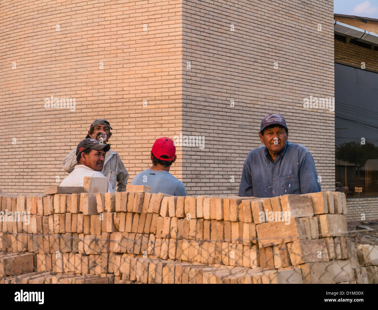 Vier Hispanic Bauarbeiter, Baseball Mützen tragen, stehen vor einer Baustelle in dieser Stadt mit einem starken deutschen Einflusses. Stockfoto