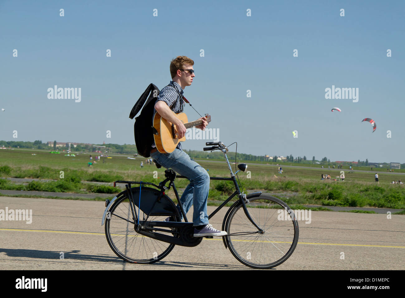 Gitarrist mit dem Fahrrad auf dem Rollfeld des ehemaligen Flughafen Tempelhof in Berlin Deutschland Stockfoto