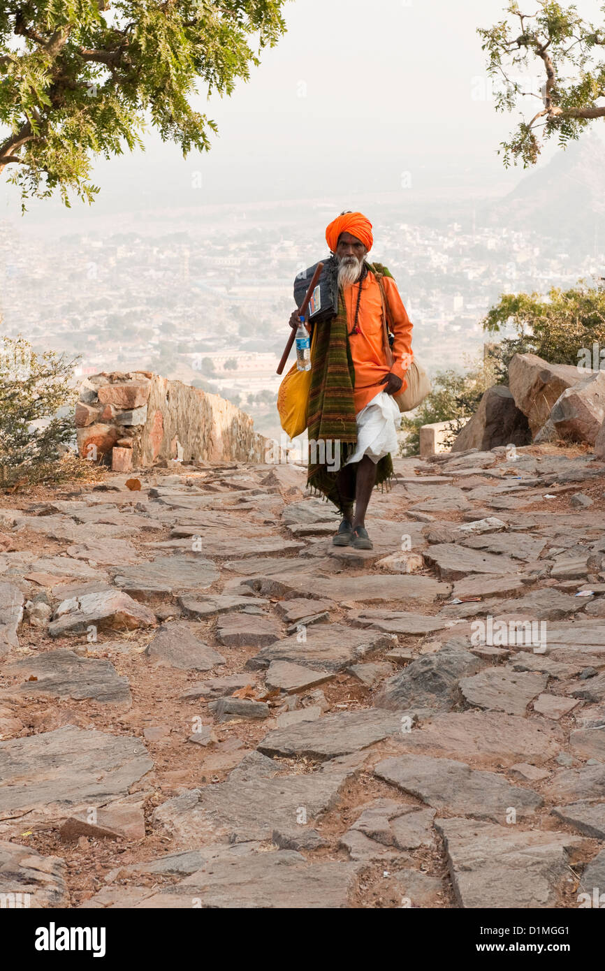 Ein Sadhu (hinduistischen heiligen Mann) zu Fuß auf einem gepflasterten Weg in seinem orangefarbenen Gewand und Turban in der Nähe von Pushkar Rajasthan Indien Stockfoto Ein Sadhu (hinduistischen heiligen Mann) zu Fuß auf einem gepflasterten Weg in seinem orangefarbenen Gewand und Turban in der Nähe von Pushkar Rajasthan Indien Stockfoto