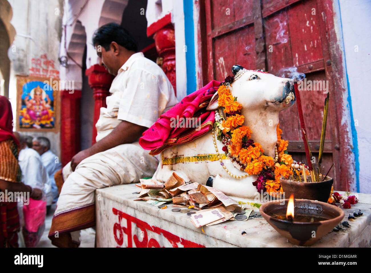 Ein Hindu Mann sitzt neben einem Bildnis einer Kuh vor einem Tempel in der Heiligen Stadt Pushkar Indiens Stockfoto Ein Hindu Mann sitzt neben einem Bildnis einer Kuh vor einem Tempel in der Heiligen Stadt Pushkar Indiens Stockfoto