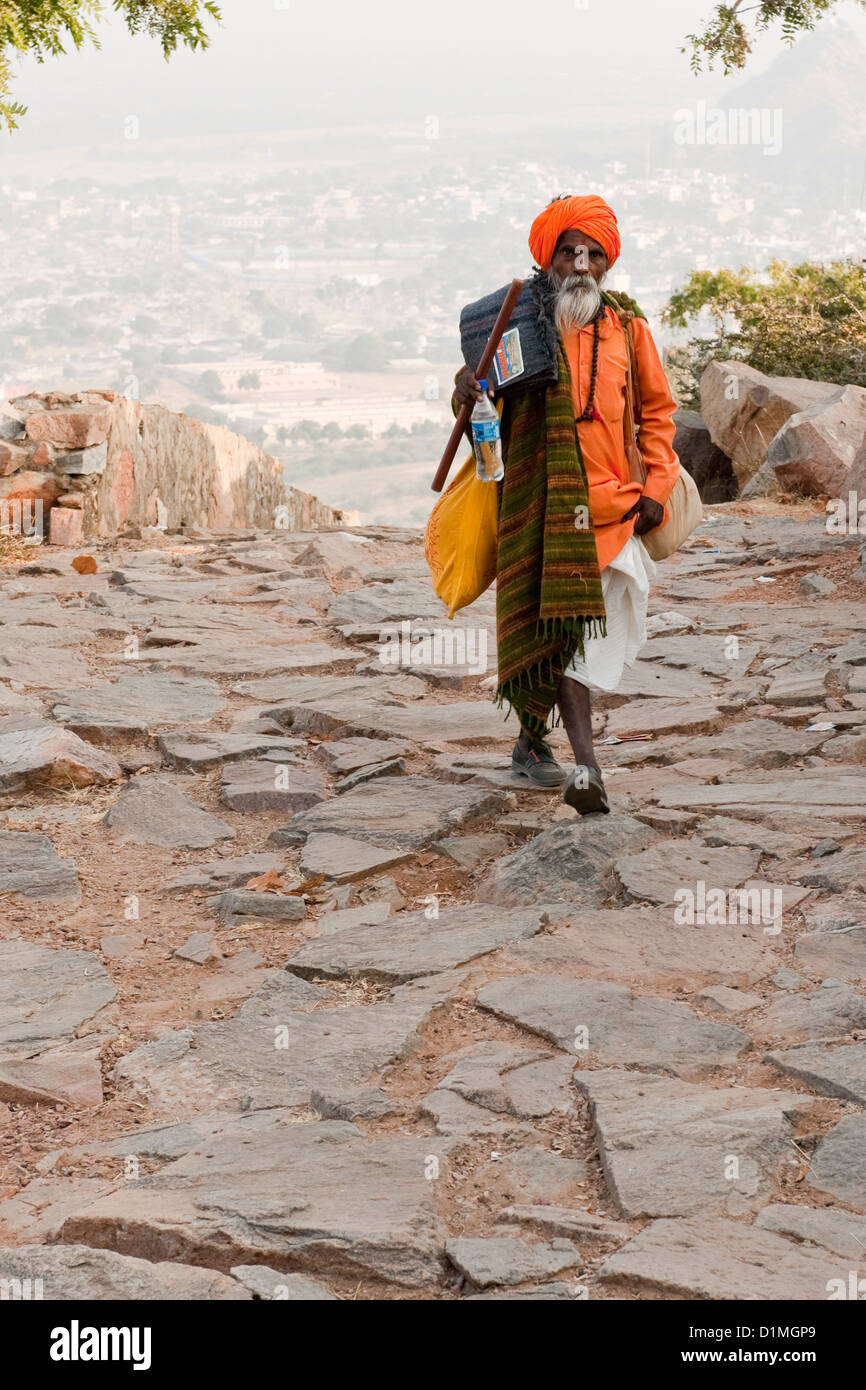 Ein Sadhu (hinduistischen heiligen Mann) zu Fuß auf einem gepflasterten Weg in seinem orangefarbenen Gewand und Turban in der Nähe von Pushkar Rajasthan Indien Stockfoto