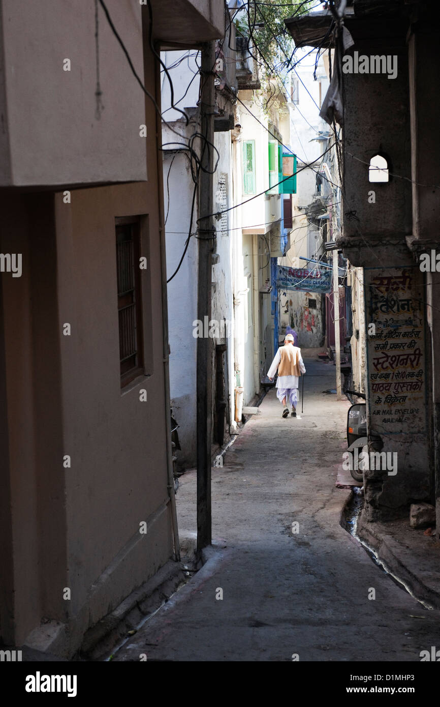 Einer alten indischen Mann in traditioneller Kleidung geht auf einen engen Verbündeten in Udaipur, Rajasthan, Indien Asien Stockfoto