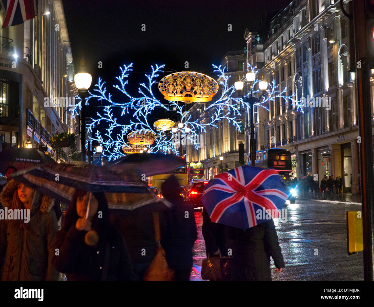 Weihnachts-Einkäufer und Union Jack Flagge Regenschirm in einem Regen fegte die Regent Street mit Weihnachtsbeleuchtung hinter London UK Stockfoto