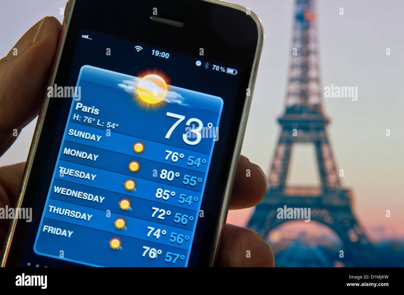PARIS Roaming Wetter Smartphone Eiffelturm Dämmerung Hand hält Apple iPhone mit Bildschirm zeigt Woche der Urlaubssonne auf Wetter-Anwendung Stockfoto