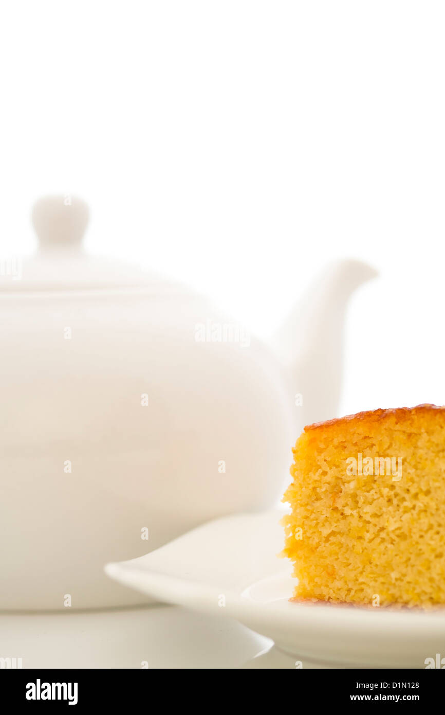 Clementine, Zitrone, Mandel-Kuchen auf einem weißen Teller mit einem weißen Teekanne auf weißem Hintergrund Stockfoto