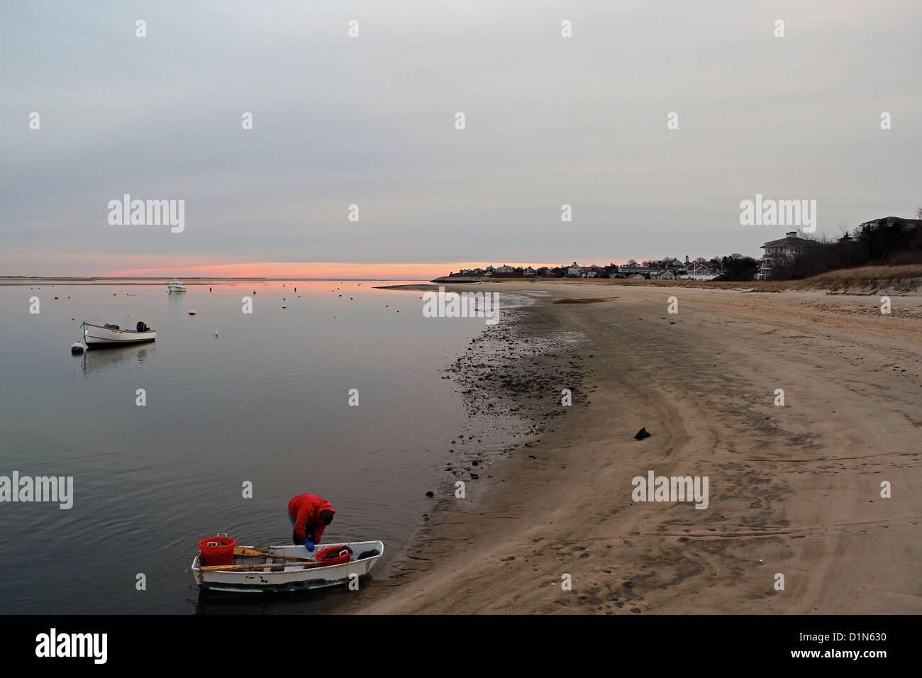 Ein Mann bringt ein kleines Boot zum Ufer bei Sonnenuntergang in der Nähe von Chatham Fish Pier, Cape Cod, Massachusetts Stockfoto
