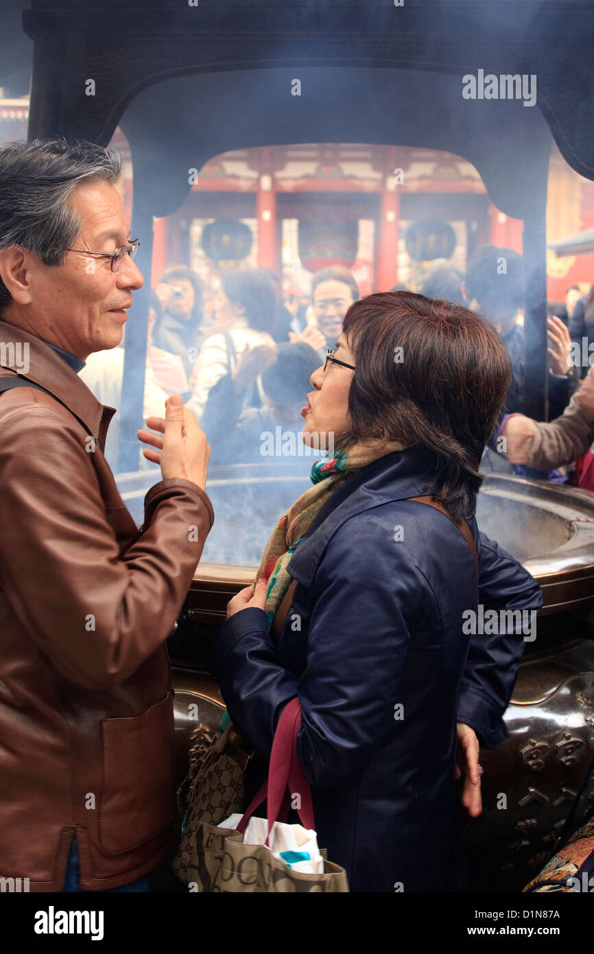 Paar Einatmen Weihrauch in einem Tempel in Tokio für eine gute Gesundheit Stockfoto