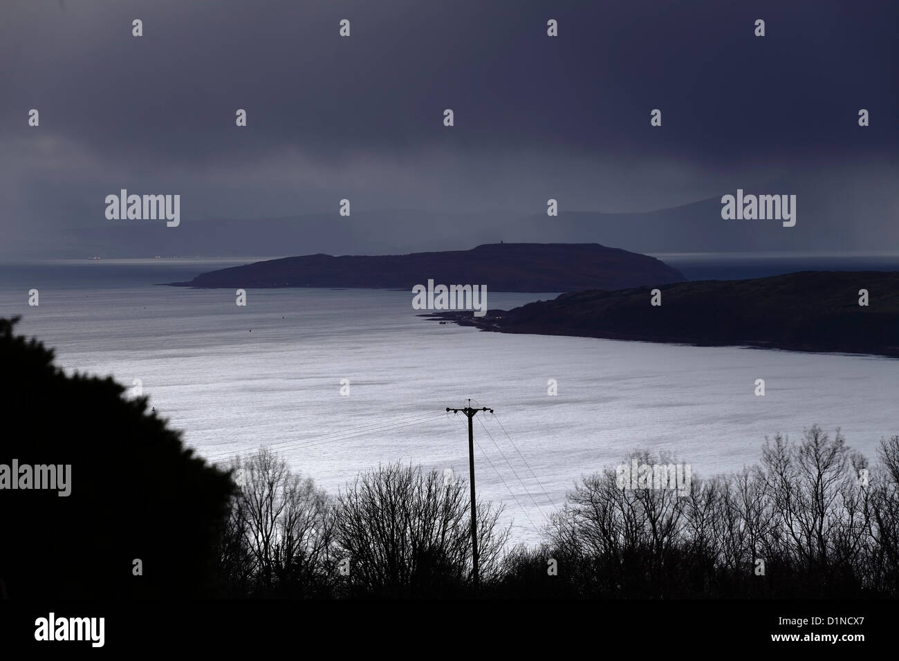 Firth of Clyde, Largs, North Ayrshire, Schottland, Großbritannien, Montag, 31. Dezember 2012. Dunkler Himmel über dem Firth of Clyde in der Abenddämmerung am letzten Tag des 2012. Hinter den Bäumen befinden sich rechts die Inseln Great Cumbrae, in der Mitte Little Cumbrae und im Hintergrund Arran Stockfoto