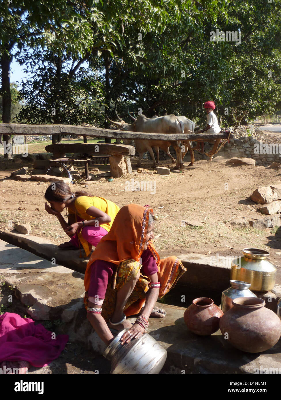 RAJASTHAN, Indien - DEC 3 - alte Indianerin Hols Wasser aus Brunnen in Metall Töpfe, am 3. Dezember 2009, in Rajasthan, Indien Stockfoto