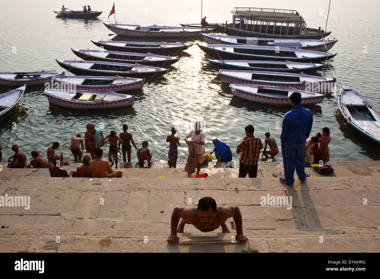 In Varanasi finden jeden Morgen unter den Menschen im heiligen Ganges Baden Sie Menschen Yoga praktizieren und Wahrnehmung in der Öffentlichkeit. Stockfoto