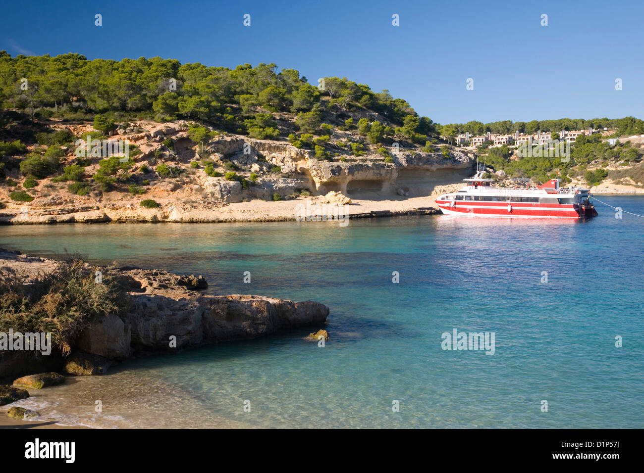 Magaluf, Mallorca, Balearen, Spanien. Blick über das türkisfarbene Wasser des Cala Portals Vells, bunte Boot vor Anker. Stockfoto