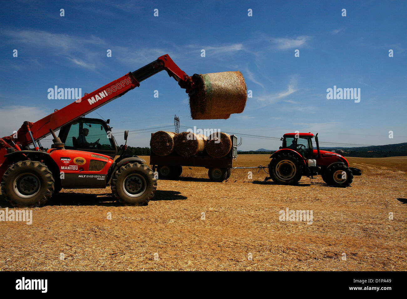 Traktor hat runden Strohballen beladen Stockfoto