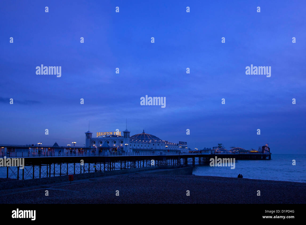 Pier von Brighton Vergnügen in der Abenddämmerung mit paar saß Silhouette am Strand, Brighton, East Sussex, England Stockfoto