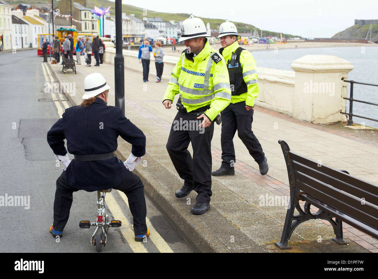 Polizisten in Isle Of Man haben weiße Helme, einschließlich einen Clown verkleidet als Polizist auf kleinen Fahrrad Stockfoto