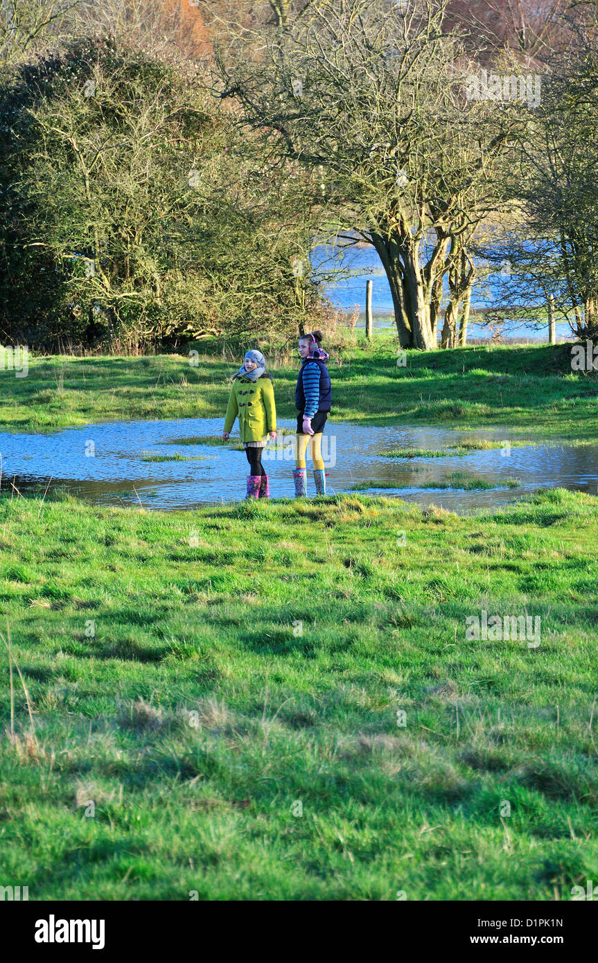 Kinder auf einem Neujahr 2013 laufen neben der überfluteten River Windrush zwischen Burford und Swinbrook, Cotswolds, Oxon, UK Stockfoto