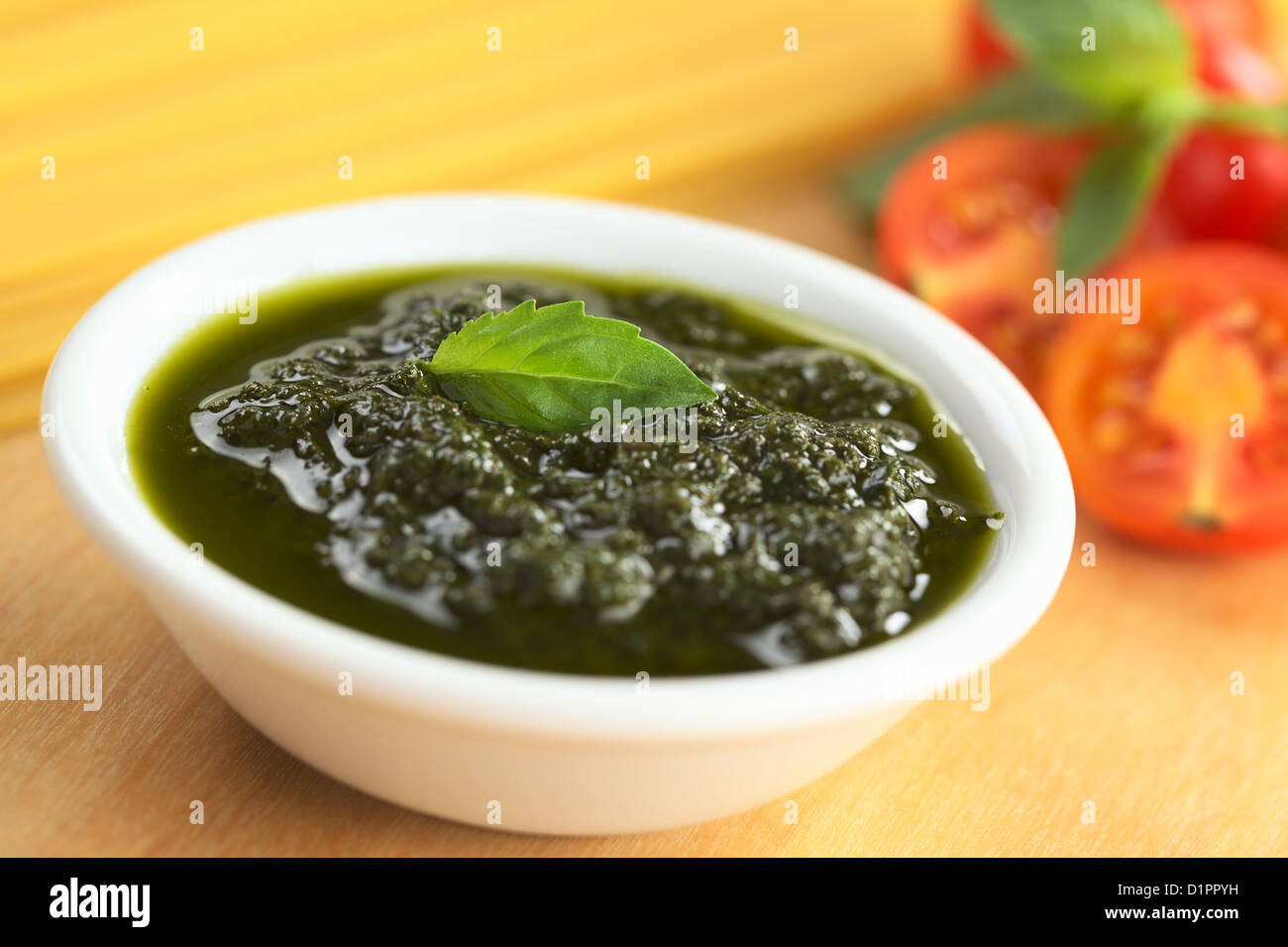 Frisches Pesto aus Basilikum, Knoblauch und Olivenöl in eine kleine Schüssel geben und mit einem Blatt Basilikum garniert Stockfoto