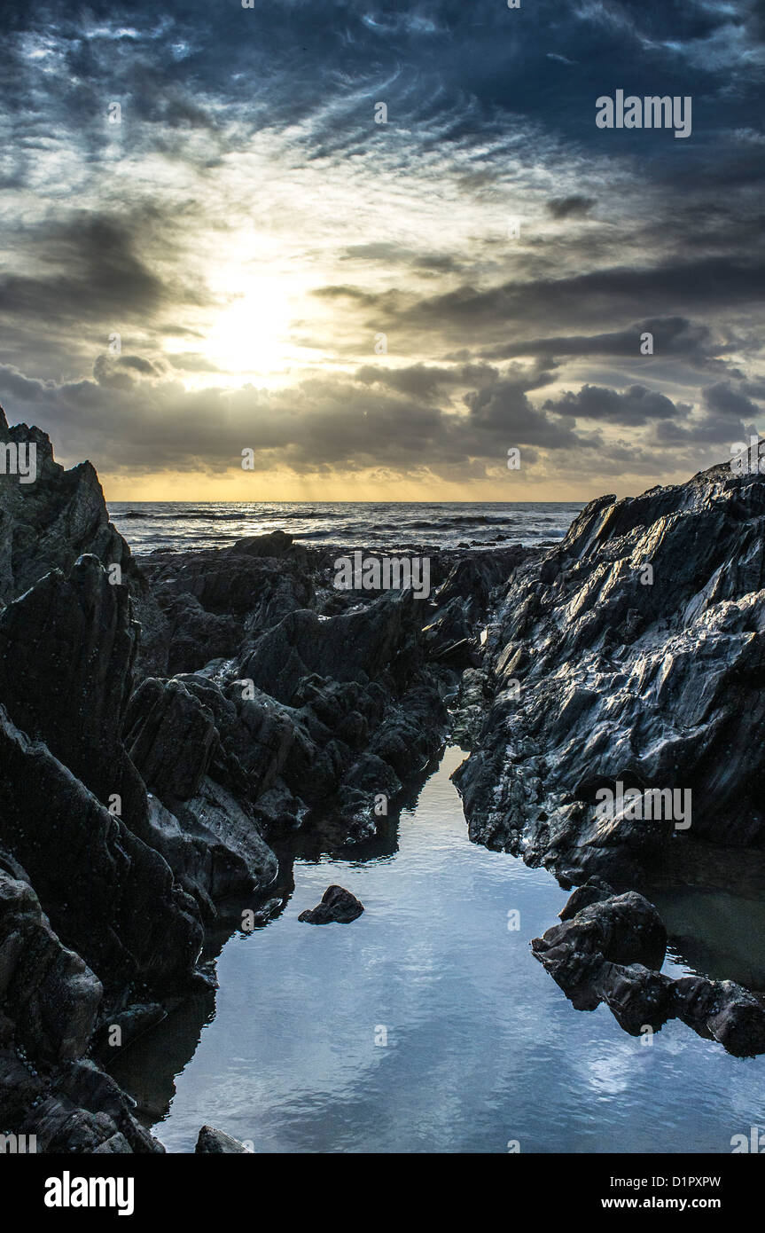 Dramatische Aussicht auf den Sonnenuntergang über dem Meer vom felsigen Strand. Ayrmer Cove, Devon. GROSSBRITANNIEN Stockfoto