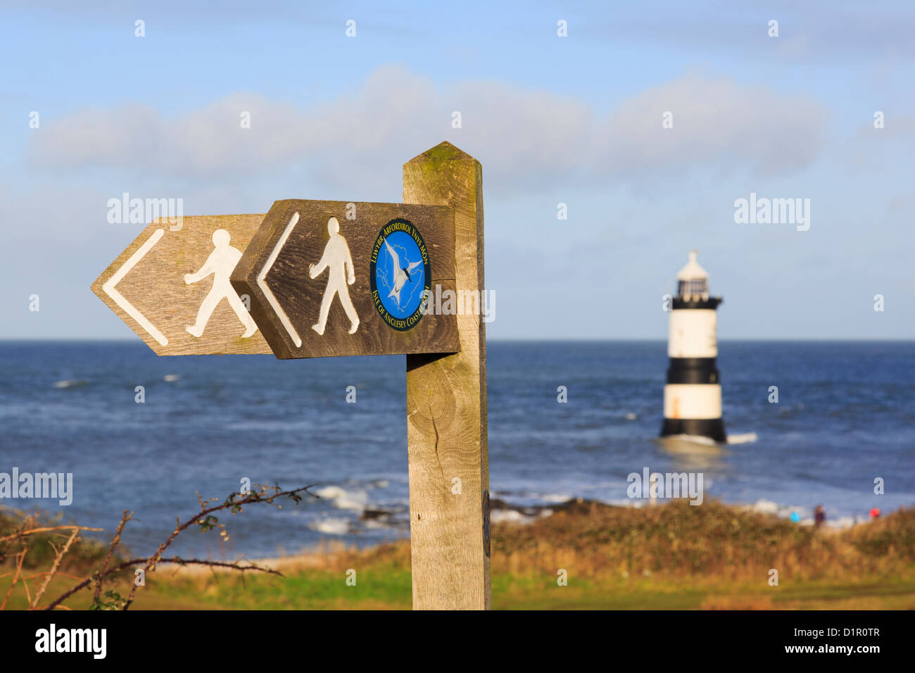Isle of Anglesey Coastal Path und Wales Küste Wanderweg Wegweiser mit Penmon Leuchtturm aus Küste darüber hinaus. Penmon Punkt ANGLESEY Wales England Großbritannien Stockfoto
