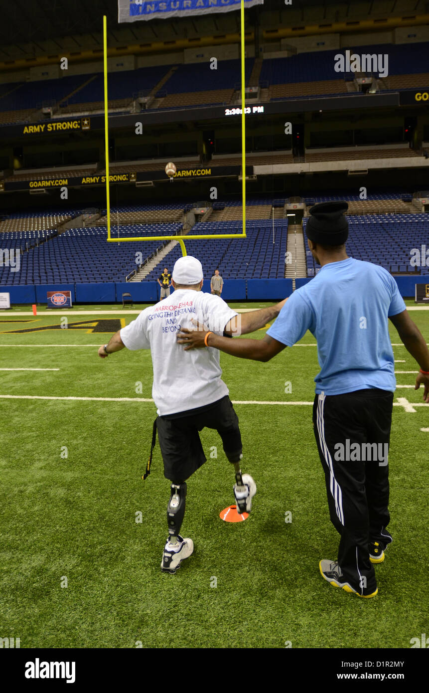 US Army Reserve Spc Justin Lane (links) bereitet sich auf einen Fußball mit Hilfe von Highschool-Football-Spieler Kameron Miles an der Alamodome in San Antonio 2. Januar 2013 punt. Meilen, ein Dallas stammende gehört zu 90 Nachwuchsathleten, die ausgewählt wurden, zur Teilnahme an der US-Armee All-American Bowl, Jan. 5 stattfinden. Lane und anderen verwundeten Krieger teamed oben mit den Nachwuchsathleten für Fußball-Herausforderungen, darunter Stechkahn fahren, tretend und werfen. Die Armee hat der All-American Bowl in San Antonio seit 2002 veranstaltet mit mehr als 1.300 Schulen bundesweit. (US Army Reserve ph Stockfoto