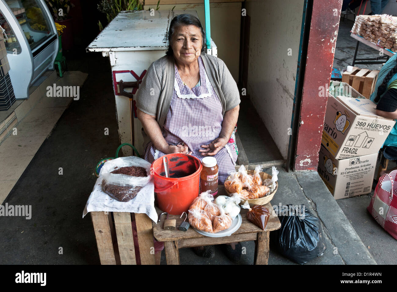 mittlere gealterte Frau Anbieter verkaufen gebratene Heuschrecken Frijoles & andere zubereitete Speisen am Eingang zum MercadoLa Merced Markt Oaxaca Stockfoto