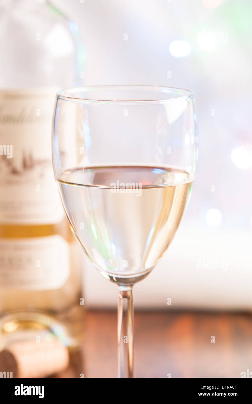 Glas und Flasche Weißwein auf hellen Hintergrund blinken Stockfoto